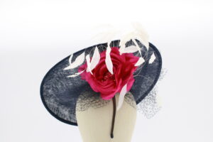 Navy sınamay fascinator base adorned with hot pink silk roses and white feathers. Attached with a headband