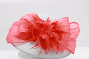 Light blue sinamay hat with coral looped ribbon and coral feathers.