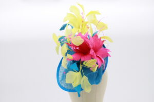 Electric blue sinamay fascinator base decorated with blue sinamay swirls, yellow feathers and hot pink feather flowers.