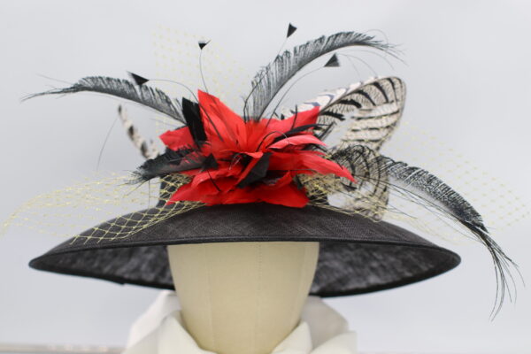 Large, black sinamay hat decorated with pheasant feathers, red feather bow, white netting.